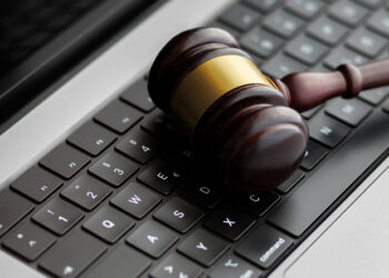 A wooden judge’s gavel lying on a laptop keyboard symbolizes online law, digital justice, and modern legal decisions in cyberspace.