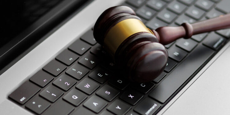 A wooden judge’s gavel lying on a laptop keyboard symbolizes online law, digital justice, and modern legal decisions in cyberspace.